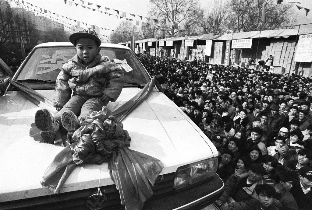 1997年，北京街頭的彩票開(kāi)獎(jiǎng)現(xiàn)場(chǎng)，四川來(lái)京務(wù)工人員伍富貞家3歲的孩子中得一輛轎車。胡金喜攝影像見(jiàn)證四十年.jpg